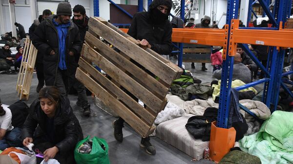 Беженцы с Ближнего Востока несут деревянные поддоны для изготовления из них кроватей в центре временного содержания мигрантов - Sputnik Аҧсны