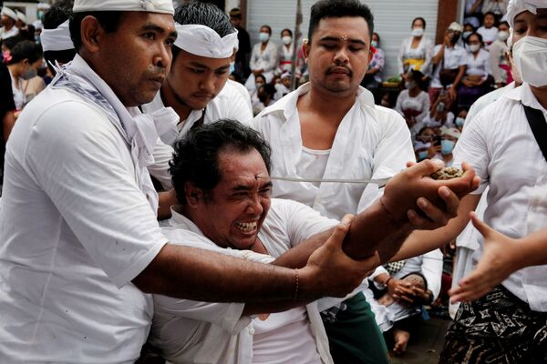 Индуист балиец пытается ударить себя в лоб традиционным кинжалом Керис во время священного ритуала Нгеребонг на Бали, Индонезия. - Sputnik Абхазия