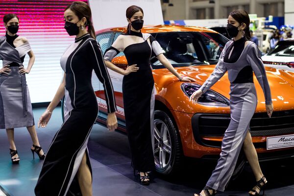 Модели проходят мимо автомобиля Porsche Macan на Таиландской  Международной автомобильной выставке 2021 года в Бангкоке 2 декабря 2021  года. - Sputnik Абхазия