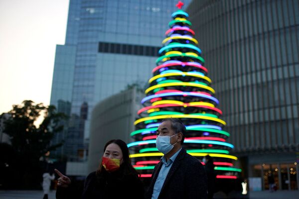 Люди стоят возле освещенной рождественской елки возле торгового центра в Шанхае. - Sputnik Абхазия