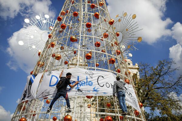 Активисты вывешивают баннер на рождественской елке во время акции  протеста против действий правительства президента Сальвадора Найиба Букеле, таких как использование биткоина и правовых реформ для продления его срока полномочий, в Сан-Сальвадоре. - Sputnik Абхазия