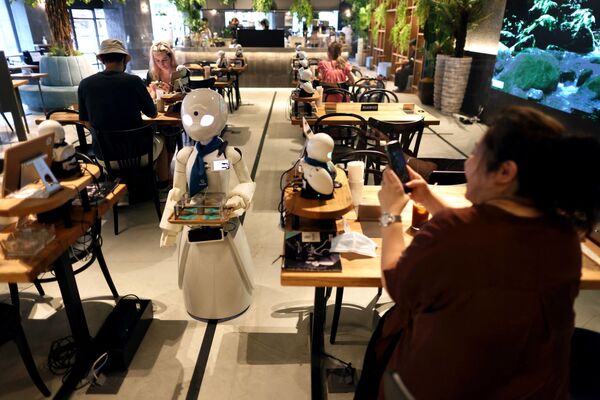 На этой фотографии, сделанной 17 августа 2021 года, робот-гуманоид разносит напитки в кафе в Токио. - Sputnik Абхазия