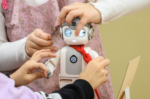 Дети играют с 24-сантиметровым роботом &quot;Альфа Мини&quot;, который умеет петь, танцевать и даже учить кунг-фу. В школе Мару в Сеуле начали использовать роботов-малышей в качестве помощников в детском саду. - Sputnik Абхазия