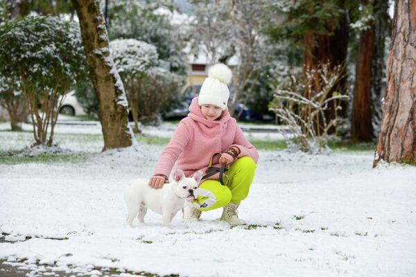 Маленькая девочка держит на поводке собачку, возможно, из-за боязни потерять питомца в белом снегу. - Sputnik Абхазия