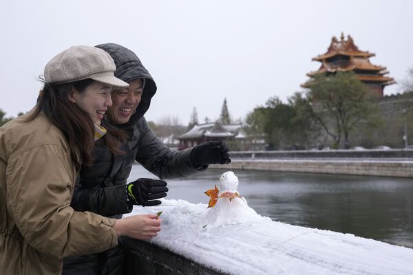 Китайская пара лепит снеговика возле Запретного города в Пекине. - Sputnik Абхазия