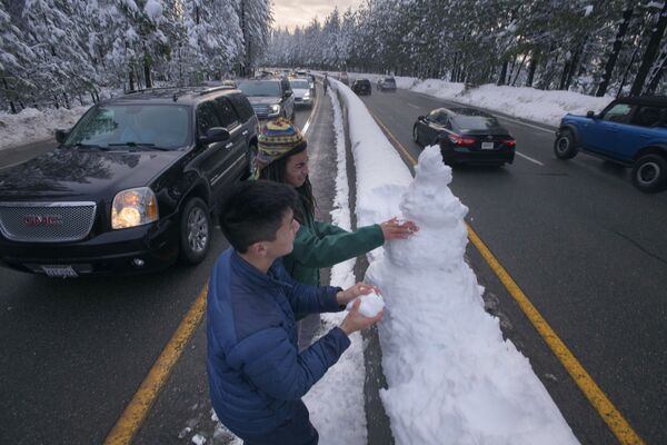 Молодые люди лепят снеговика на шоссе в Калифорнии, США. - Sputnik Абхазия