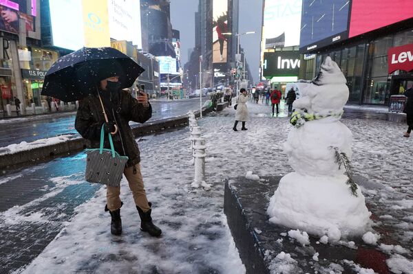 Мужчина фотографирует снеговика на Таймс-сквер в Нью-Йорке, США. - Sputnik Абхазия