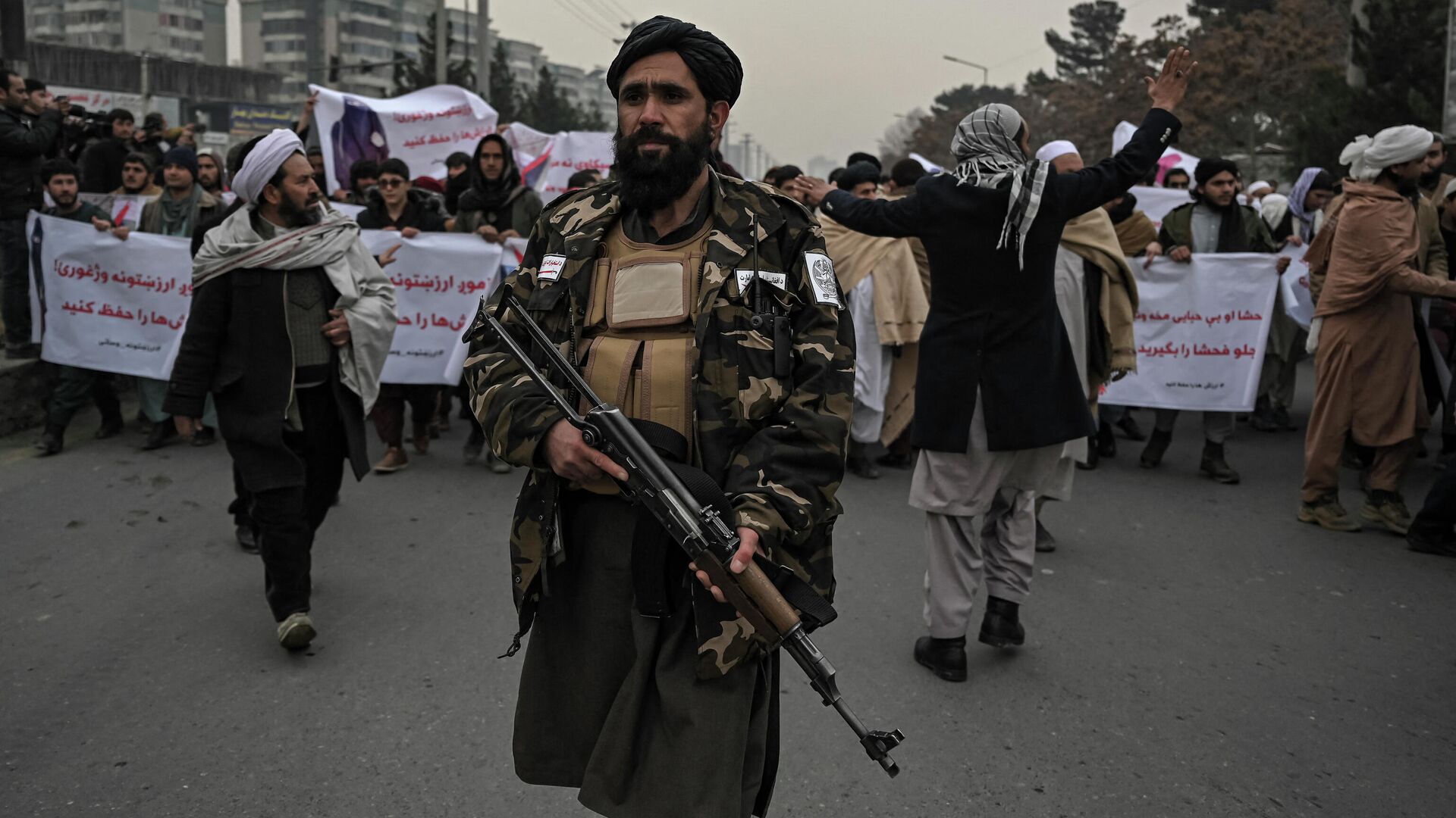Боец Талибана сопровождает людей во время демонстрации осуждения недавней акции протеста афганских активистов за права женщин в Кабуле 21 января 2022 года. - Sputnik Абхазия, 1920, 18.02.2022