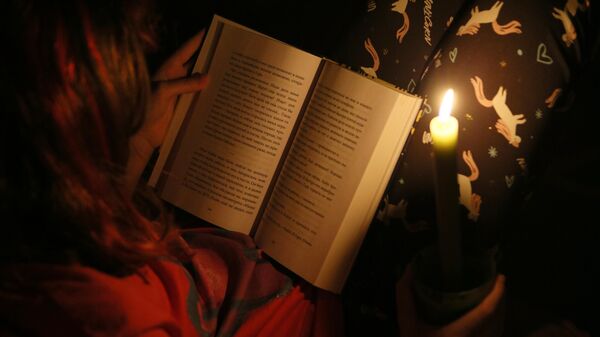 Ребенок читает книгу при свечах во время тестового отключения электричества  - Sputnik Абхазия