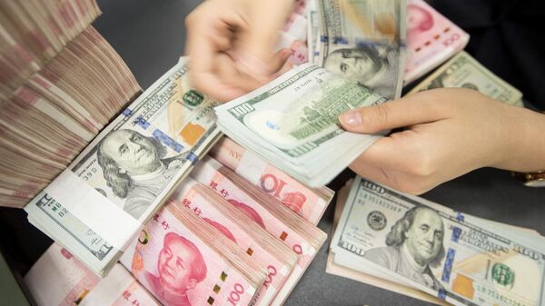 Сотрудник китайского банка пересчитывает банкноты в 100 юаней и купюры в долларах США - Sputnik Абхазия