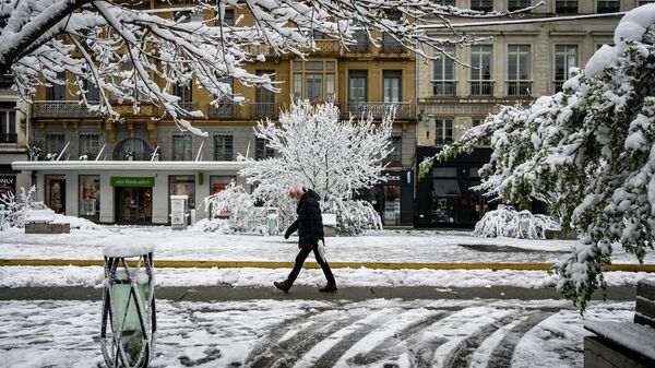 Человек идет по заснеженной улице Сент-Этьена - Sputnik Абхазия