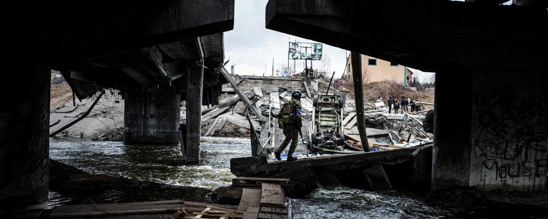 Украинский военнослужащий идет по макшифтовой тропе, чтобы пересечь реку рядом с разрушенным мостом в городе Ирпень, к северо-западу от Киева - Sputnik Абхазия, 1920, 10.04.2022