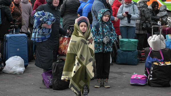 Люди стоят со своим багажом в ожидании посадки в автобусы, которые доставят их дальше в Польшу или за границу из временного приюта для беженцев - Sputnik Абхазия