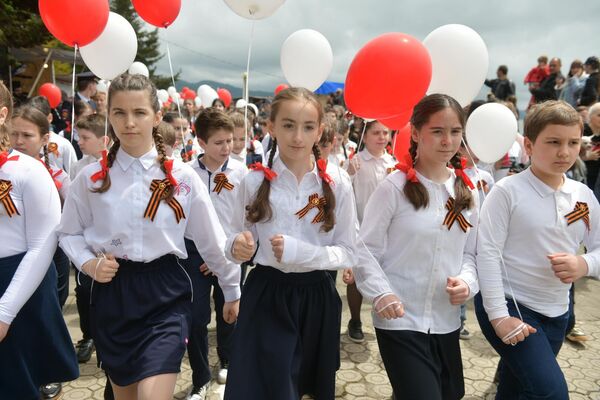 В руках школьники держали воздушные шары, а также знамена Победы. - Sputnik Абхазия