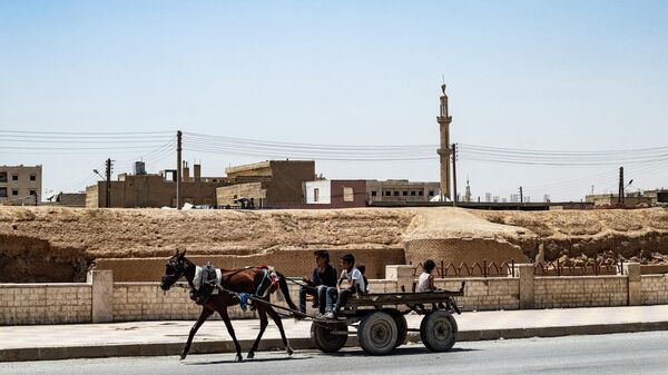 Молодежь едет на повозке, запряженной лошадьми, в городе Рака на севере Сирии, 19 июня 2022 года. - Sputnik Аҧсны