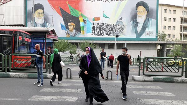 Иранцы проходят мимо рекламного щита с изображением верховного лидера Ирана аятоллы Али Хаменеи и аятоллы Рухоллы Хомейни в столице Тегерана - Sputnik Абхазия