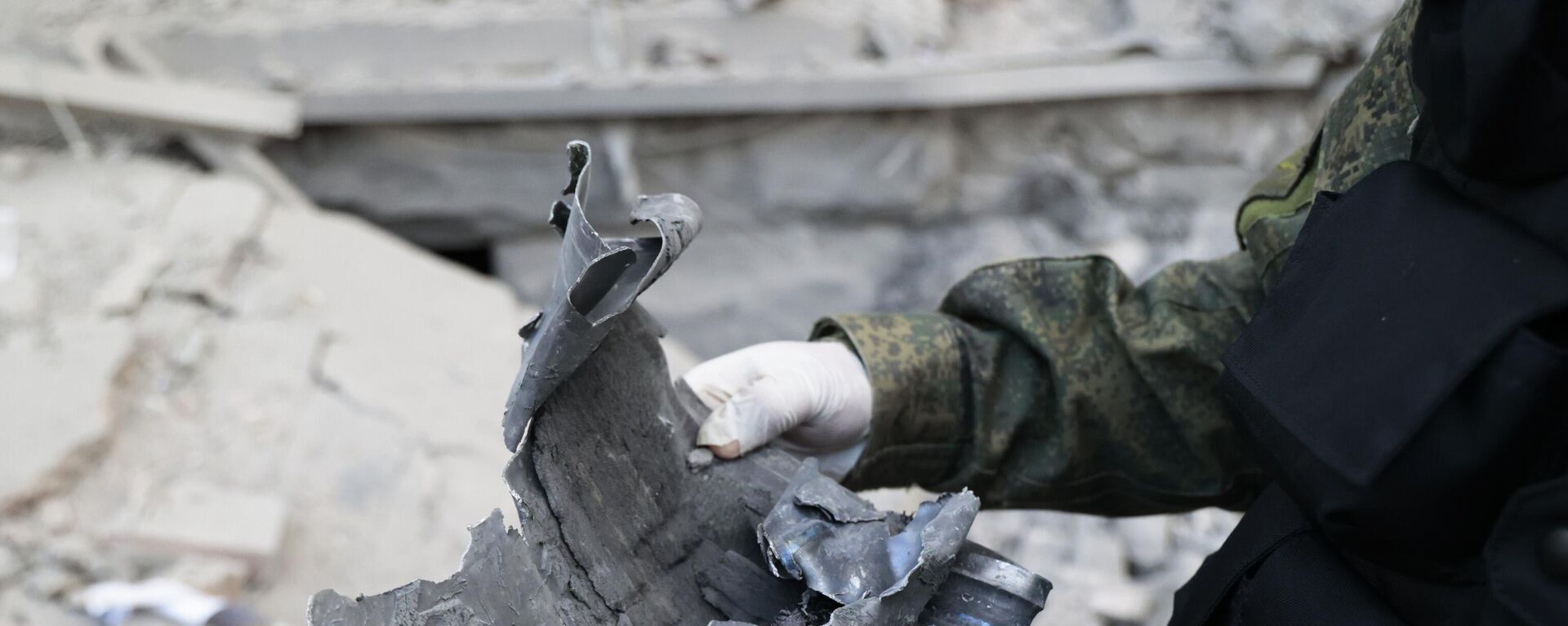 Следователь СЦ РФ демонстрирует часть снаряда на месте пострадавшего в результате обстрела со стороны ВСУ здания городской администрации в центре Донецка - Sputnik Абхазия, 1920, 15.12.2022