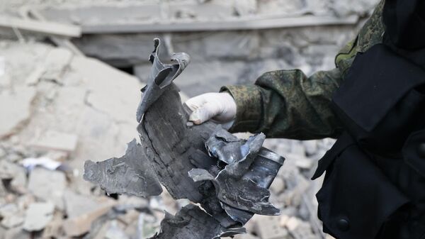 Следователь СЦ РФ демонстрирует часть снаряда на месте пострадавшего в результате обстрела со стороны ВСУ здания городской администрации в центре Донецка - Sputnik Абхазия