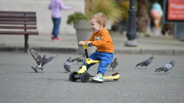 Ребенок гоняет голубей на площади Багапша  - Sputnik Аҧсны