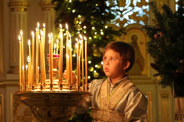 Мальчик зажигает свечу во время празднования православного Рождества в Русской православной церкви в Шардже. - Sputnik Абхазия