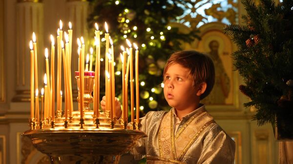 Мальчик зажигает свечу во время празднования православного Рождества в Русской православной церкви в Шардже - Sputnik Абхазия