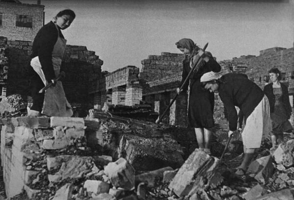Женщины работают на улицах разрушенного города, разбирая руины жилых домов. - Sputnik Абхазия