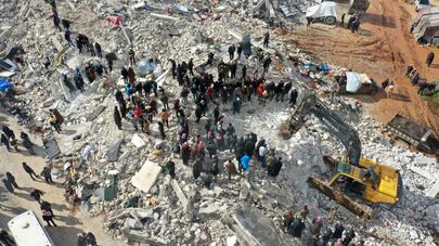 На этом снимке с воздуха показаны жители, ищущие жертв и выживших среди обломков разрушенных зданий после землетрясения в деревне Бесния недалеко от города Харим в удерживаемой повстанцами северо-западной сирийской провинции Идлиб на границе с Турцией, 6 февраля 2022 года.