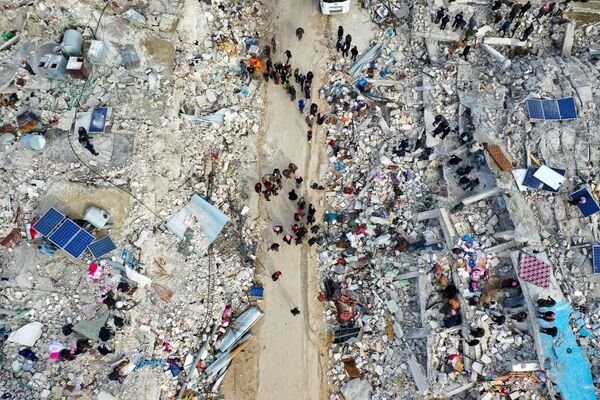 Жители, ищут выживших среди обломков разрушенных зданий после землетрясения в деревне Бесния недалеко от города Харим в Сирии. - Sputnik Абхазия