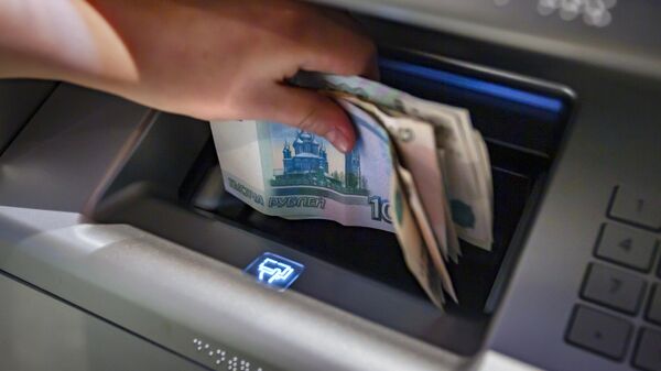 Посетитель кладет деньги на банковский счет в банкомате на территории торгового центра Центральный детский магазин. - Sputnik Абхазия