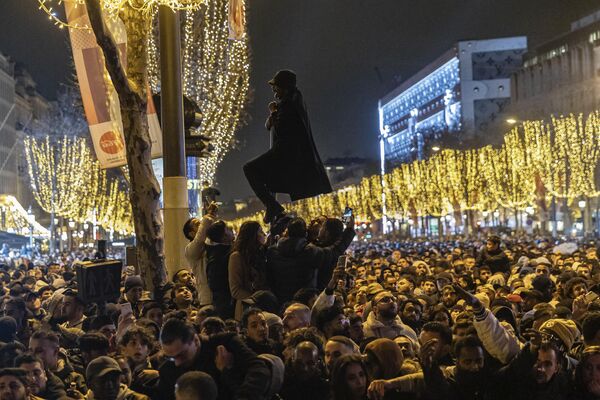 Мужчина взбирается на столб во время празднования Нового года в Париже, Франция. - Sputnik Абхазия