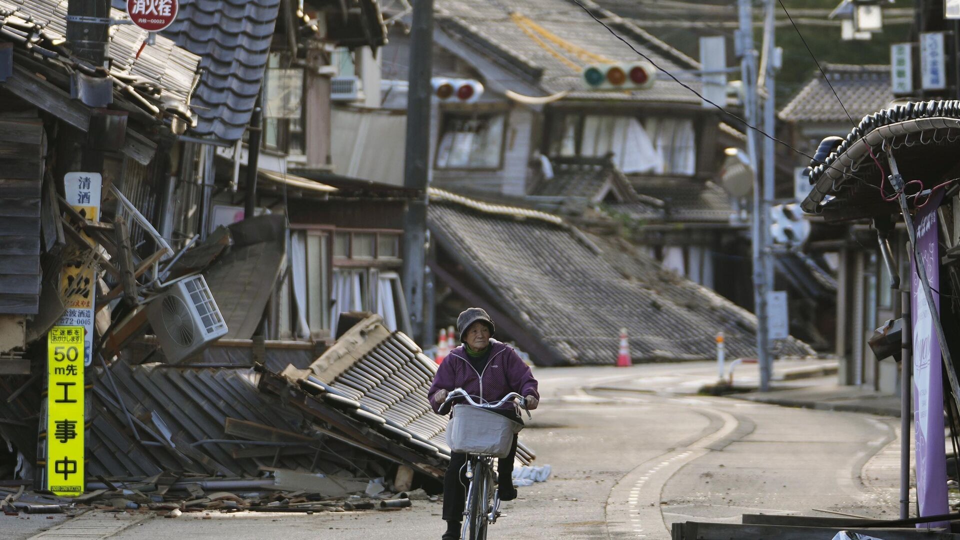 Женщина едет на велосипеде среди поврежденных домов в городе Ното на полуострове Ното - Sputnik Аҧсны, 1920, 04.01.2024