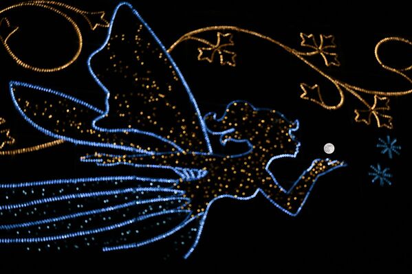 В Лондоне на ночном небе появляется полная луна, идеально расположенная за городским фонарем в форме феи. Кажется, что фея дует в сторону луны, создавая волшебный и сказочный эффект. Урбанистический пейзаж контрастирует с небесным светом, подчёркивая игру между городскими огнями и природным сиянием луны - Sputnik Абхазия