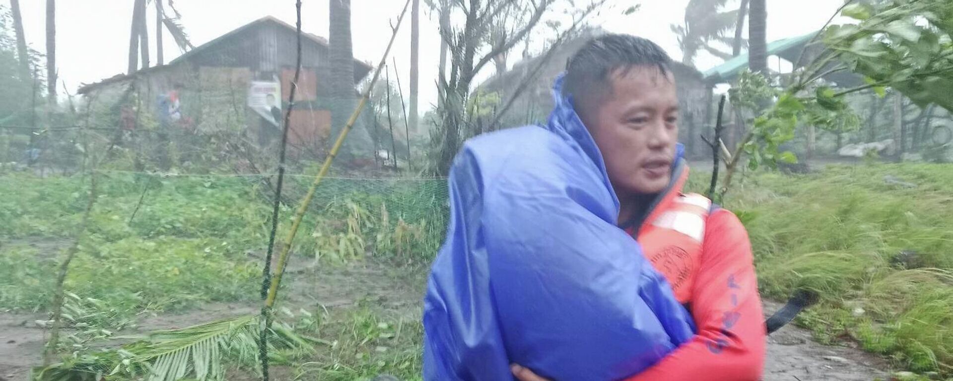 Спасатель эвакуирует ребенка в безопасное место, поскольку супертайфун Рагаса обрушился на Санта-Ану, провинция Кагаян, северные Филиппины, 22 сентября 2025 года - Sputnik Абхазия, 1920, 18.12.2025