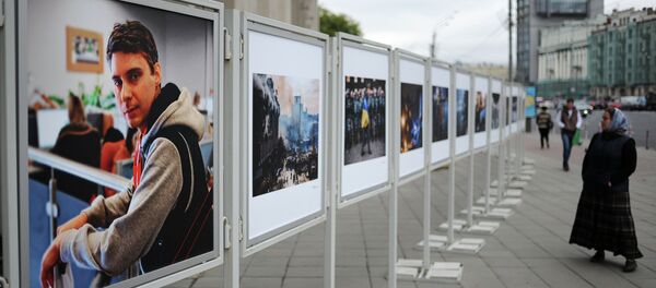 Жительница Москвы рассматривает работы погибшего на Украине фотокорреспондента Андрея Стенина у здания МИА Россия сегодня. Архивное фото. Жительница Москвы рассматривает работы погибшего на Украине фотокорреспондента Андрея Стенина у здания МИА Россия сегодня. Архивное фото. - Sputnik Абхазия