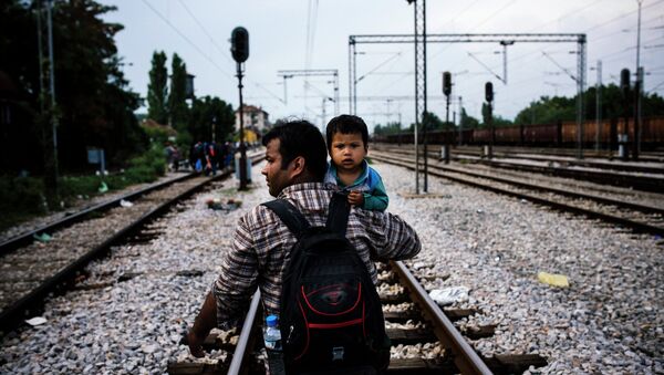 Мигрант с ребенком идет по рельсам в направлении города Гевгелия, на Македонский-греческой границе. 3 августа 2015 года. - Sputnik Абхазия
