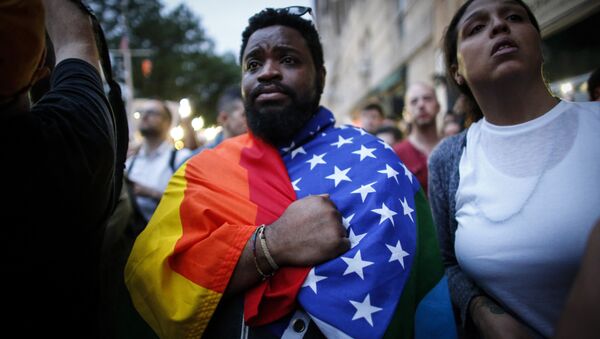 Мужчина держит флаг в знак солидарности жертв, погибших в ночном клубе Pulse в Орландо в Нью-Йорке 13 июня 2016 - Sputnik Абхазия