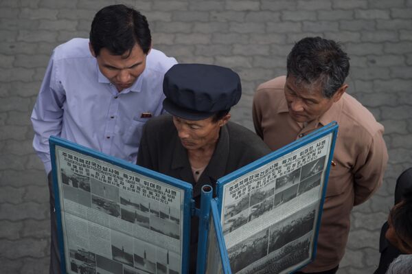 Люди у газетного киоска на улице читают копию газеты Нодон синмун, в которой рассказывается о ракетном испытании Северной Кореи 14 мая в Пхеньяне - Sputnik Абхазия