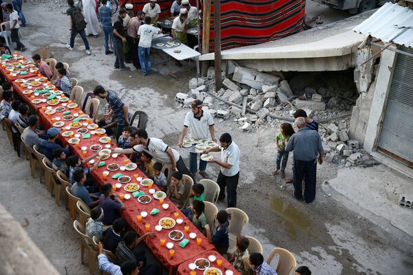 Люди собираются на Ифтар среди поврежденных зданий во время священного месяца Рамадан в мятеже, где находился осажденный район Доума - Sputnik Абхазия