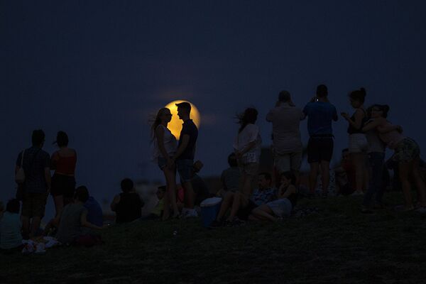 Люди наблюдают за восхождением полной луны во время ее частичного затмения на вершине холма в парке в Мадриде. - Sputnik Абхазия