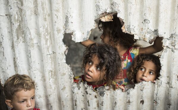 Палестинские дети смотрят через отверстие в заборе из листового металла - Sputnik Абхазия