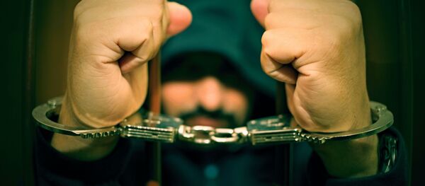 Мужчина в капюшоне в наручниках за решеткой Мужчина в капюшоне в наручниках за решеткой - Sputnik Абхазия