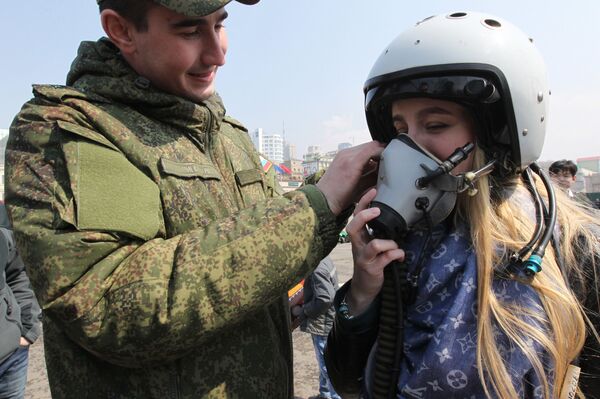 Военнослужащий помогает девушке примерить летный шлем на выставке боевой техники на центральной площади Владивостока - Sputnik Абхазия