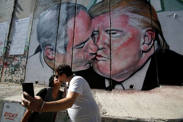 Туристы фотографируются у граффити с изображением поцелуя израильского премьер-министр Биньямина Нетаньяху и президента США Дональда Трампа на стене Вифлеема, Палестина - Sputnik Абхазия