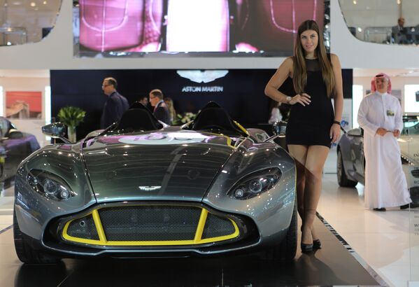 Модель стоит рядом с Aston Martin на Международном автосалоне в Дубае - Sputnik Абхазия