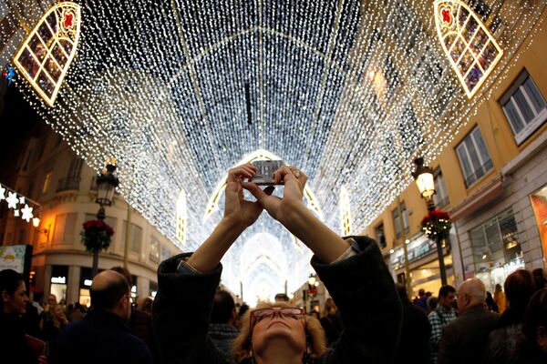 Женщина фотографирует рождественские гирлянды на улице Маркес де Лариос в Малаге, Испания - Sputnik Абхазия