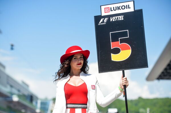 Девушка держит табличку с номером места гонщика на трассе перед гонкой на российском этапе чемпионата мира по кольцевым автогонкам в классе Формула-1 - Sputnik Абхазия
