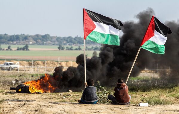 Палестинские демонстранты размахивают национальным флагом у границы между Израилем и Сектором Газа - Sputnik Абхазия