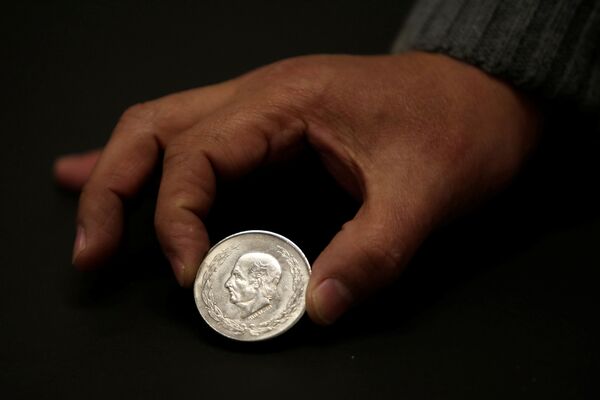 Мужчина показывает мексиканскую серебряную монету Идальго 5 песо в магазине обмена валюты в Сьюдад-Хуаресе, Мексика - Sputnik Абхазия