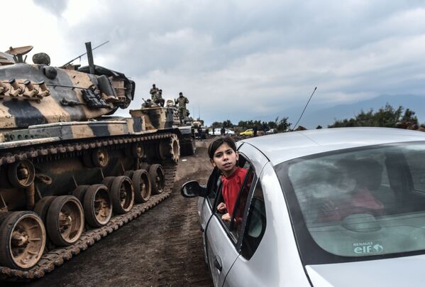 Турецкая девочка наблюдает из окна автомобиля, как танки и солдаты турецкой армии собираются у сирийской границы в городе Хасса - Sputnik Абхазия