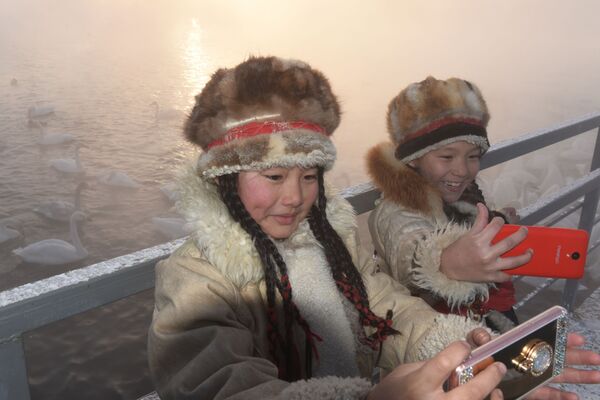 Туристы фотографируются на фоне зимующих лебедей-кликунов на Лебедином озере в Алтайском крае - Sputnik Абхазия